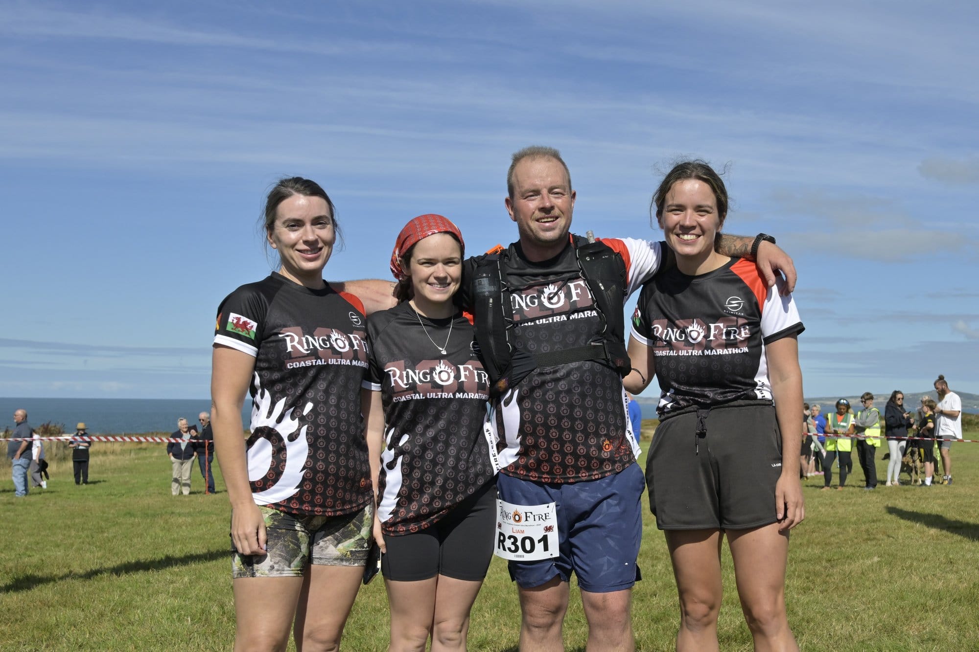 The winning relay team, four runners in Ring O' Fire shirts, smiling on a clifftop field with the sea behind them